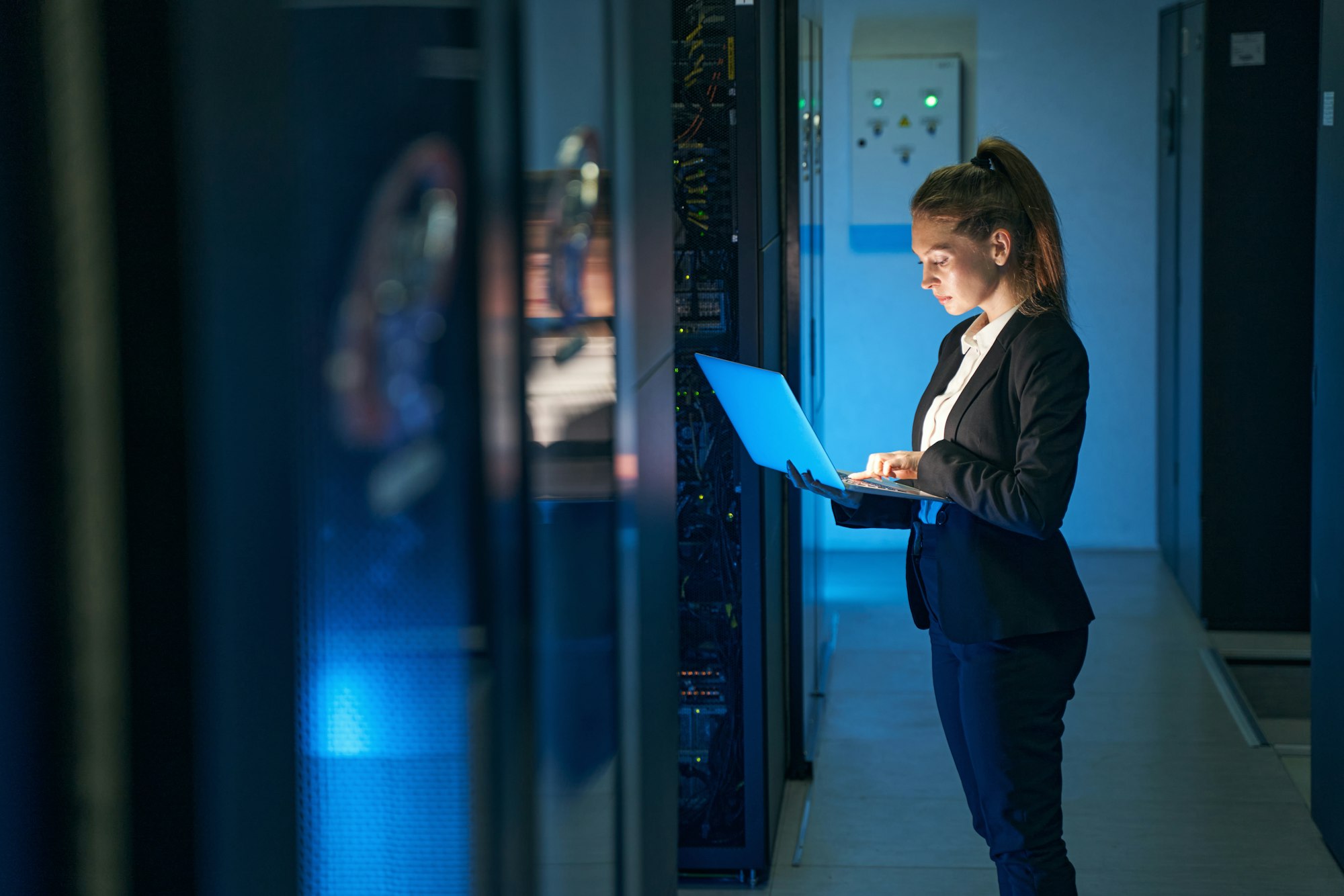 Female engineer working in server room at modern data center