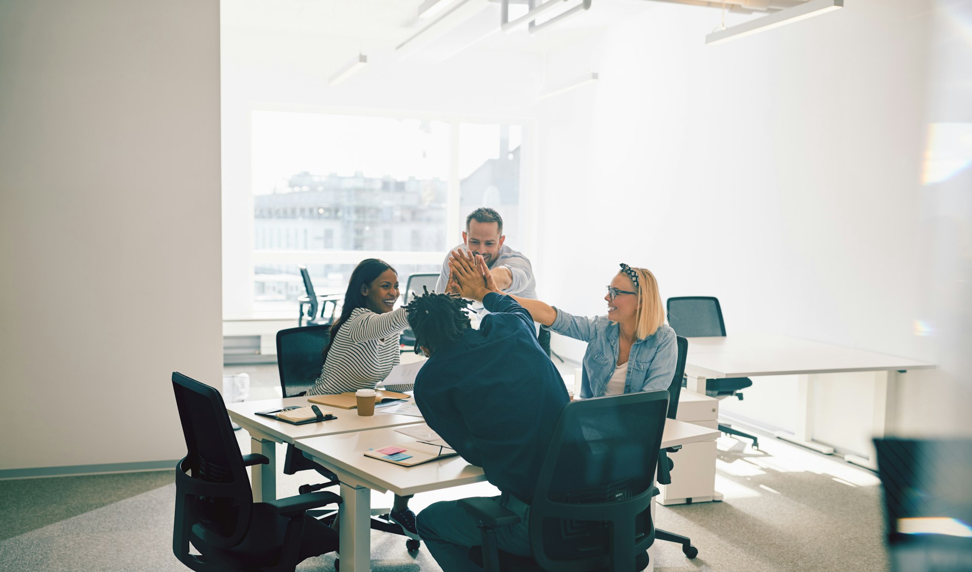 Group of smiling colleagues high fiving during an office meeting