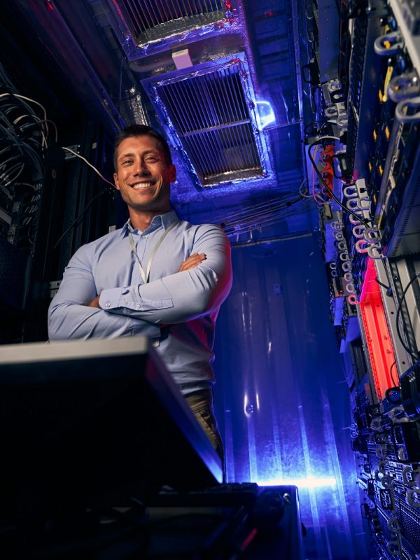 Happy IT technician standing in server room